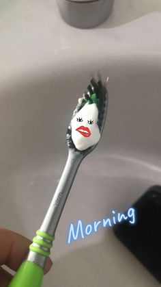 a person holding a toothbrush with the word morning on it in front of a sink