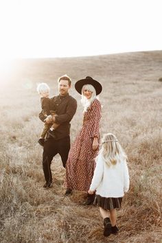 a man, woman and child standing in a field