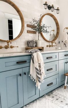 a bathroom with blue cabinets and two round mirrors