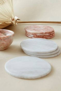 marble coasters and bowls sit on a table next to an open parasol fan