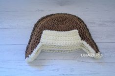 a brown and white crocheted hat on top of a wooden table