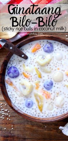 a bowl filled with fruit and milk on top of a wooden table next to a spoon