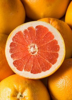 a grapefruit cut in half sitting on top of other oranges and pieces