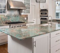 a kitchen with marble counter tops and white cabinets, along with an island in the middle