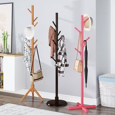 three coat racks with hats and purses on them in the corner of a room