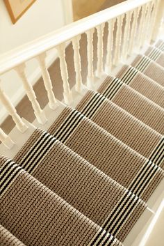 the stairs are lined with beige and black striped carpet