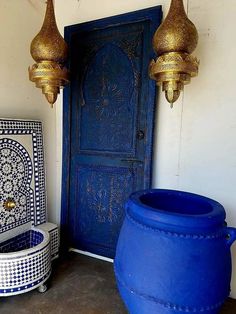 two large blue pots sitting next to each other in front of a door with gold chandeliers hanging from the ceiling