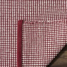 the red and white checkered fabric is folded on top of a wooden tablecloth