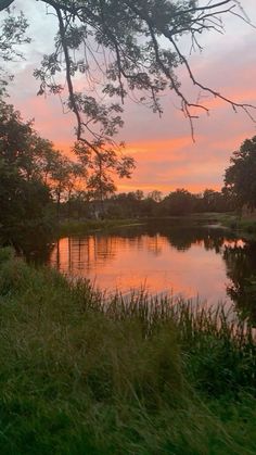 the sun is setting over a small lake