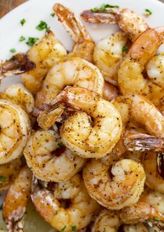 a white plate topped with cooked shrimp and garnished with parsley