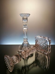 an ornate glass candle holder is shown on a reflective surface with the light behind it