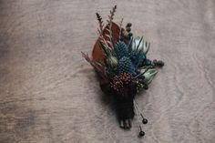 a boutonniere with flowers and leaves on a wooden surface, top view