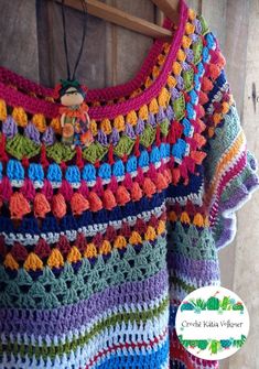 colorful crocheted sweater hanging on wooden wall