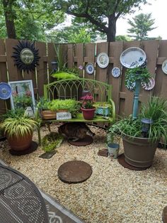 an outdoor garden with potted plants and pictures on the fence, along with other decorative items