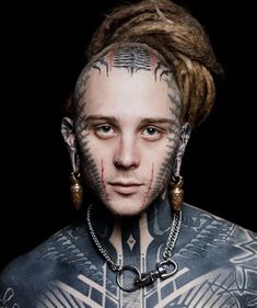 a man with tattoos and piercings on his face is looking at the camera while wearing chains around his neck