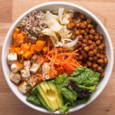 a white bowl filled with lots of different types of food on top of a wooden table