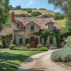 a stone house with green shutters and ivy growing on it's roof, surrounded by greenery