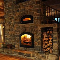 a stone oven with logs stacked in it's front and side doors open to the kitchen