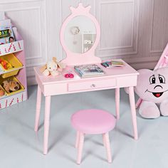 a pink desk with a mirror, stool and teddy bear in the corner next to it