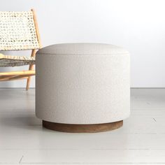 a white stool sitting on top of a wooden floor next to a wicker chair