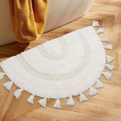 a white rug with tassels is on the floor next to a bathtub