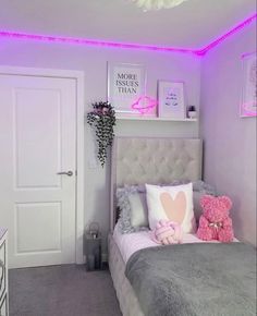 a bedroom decorated in pink and grey with lights on the ceiling, teddy bear sitting on the bed