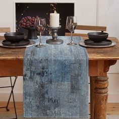 a wooden table topped with two wine glasses next to a plate and bowl filled with grapes