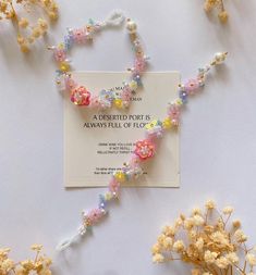 flowers and beads are arranged on a card with a name tag in the middle that says,