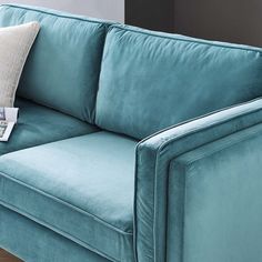 a blue couch sitting on top of a hard wood floor next to a lamp shade