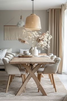 a dining room table with chairs and vases on it in front of a couch