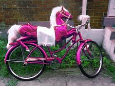 a blue and white toy horse on a bike parked in front of a brick building