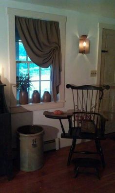 a living room with a chair and a table in front of a window next to a trash can