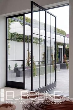 an open glass door leading to a patio with potted plants on the side walk