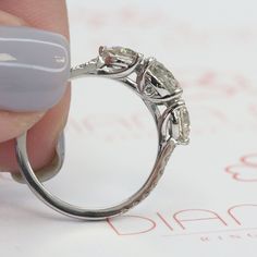 a woman's hand holding a diamond ring on top of a sheet of paper