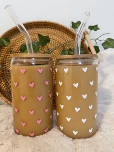 two mason jars with hearts painted on them are sitting next to a basket full of strawberries