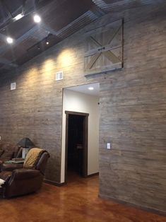 a living room filled with furniture and a wooden wall next to a doorway that leads into another room