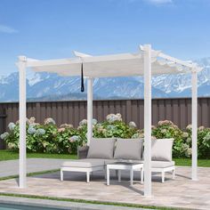 an outdoor seating area next to a pool with mountains in the background