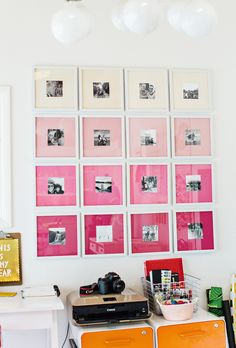 a room with many pictures hanging on the wall and a table in front of it