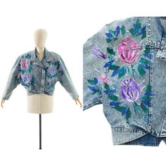 Please Enlarge Photos For More Detail D E T A I L S 1990s Jean Jacket Acid Wash Light Blue Cotton Denim Hand-Painted Roses In Pink, Purple, Green, Blue, White Decorated With Glitter Adorned With Silver-Tone Round Metal Studs + Silver-Tone Metal Set Rhinestones Lapel Collar Tapered Dolman Sleeves Attached Shoulder Pads Cropped Length Metal Snap Closures Up The Front Unlined Label: Made In Usa M E A S U R E M E N T S Fits Like A: Large Shoulders: Undefined, 17" (From End To End Of Shoulder Pads) Bust: About Up To 44/45" Waist: 33/34" Length: 19.5" To Waist, 22" To Hem Sleeve Length: 12.5" (Along Inseam), About 22" (From Edge Of Shoulder Mexican Skirts, Acid Wash Denim Jacket, Painted Roses, Cropped Coat, Hand Painted Roses, 1960's Dress, Painted Denim