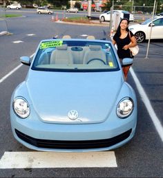 a woman standing next to a blue car in a parking lot