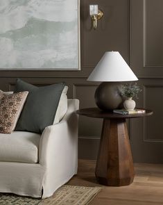 a white couch sitting next to a lamp on top of a table in a living room