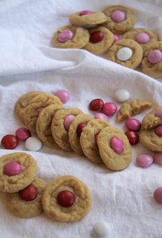 several cookies with pink and white candies are on a towel next to some candy