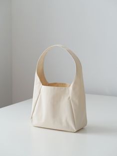 a white bag sitting on top of a table next to a wall with a light colored background