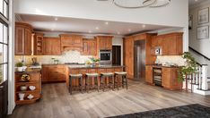 a kitchen with wooden cabinets and stools next to an open stair case in front of a window