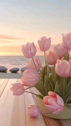 pink tulips in a vase on a wooden table near the ocean at sunset