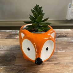 an orange fox planter with a succulent in it