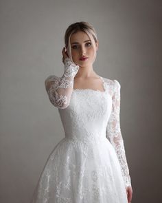 a woman in a white dress posing for the camera with her hand on her face