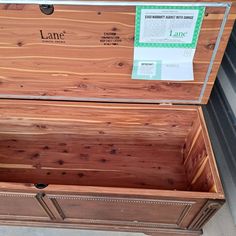 a large wooden chest with its lid open and labels on the front side, sitting outside