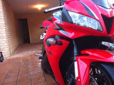 a red motorcycle parked in front of a brick building