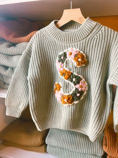 a sweater with flowers on it is hanging in a closet